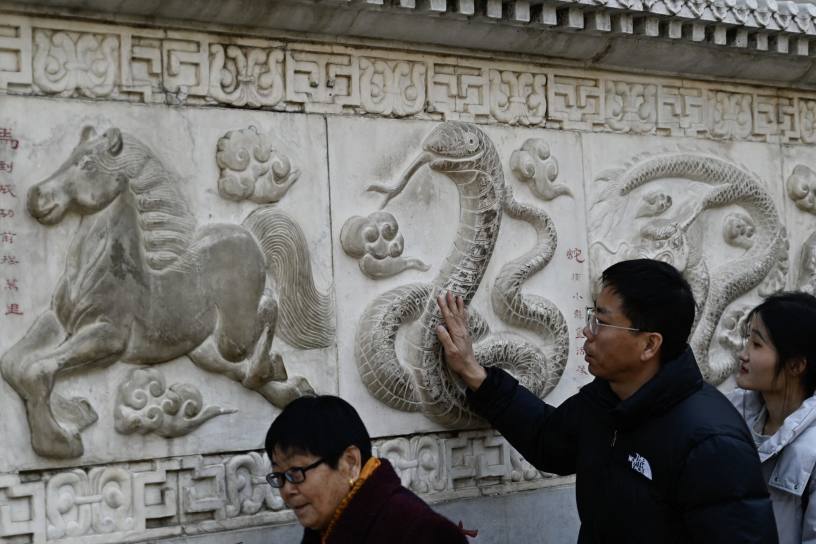 A man touches the snake figure on the stone wall depicting animals in the Chinese zodiac at the Baiyun Taoist Temple, in Beijing. Photo by Pedro Pardo/AFP via Getty Images